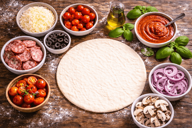 Colorful pizza toppings arranged on a prep surface